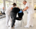 Com prevenir les caigudes en persones grans | Casal de Curació - Profesionales sanitarios ayudando a una persona mayor a levantarse durante una sesión de rehabilitación
